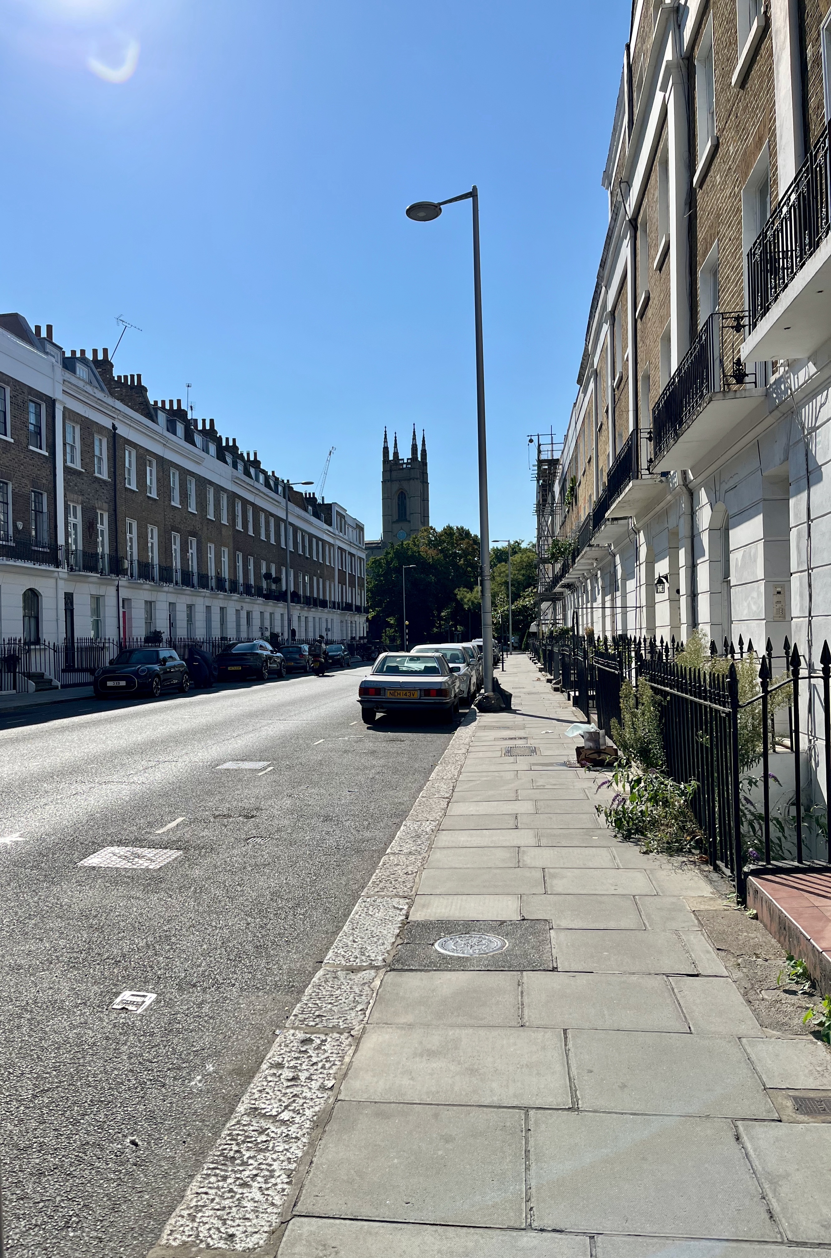 View along street of terraced homes with church in distance