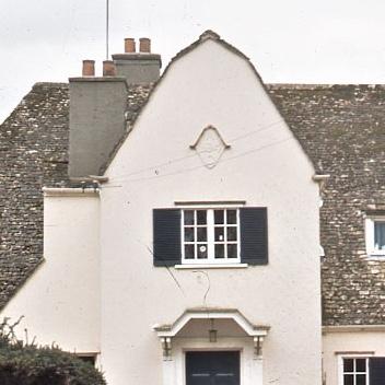Two storey house showing the top of front door and second floor window on white facade with a bit of the slate roof and chimnies around